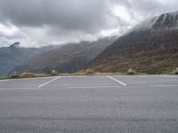 a lone skateboard parked in the middle of a road with mountains and foggy clouds