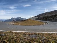 a road that is next to a mountain range and grass on the side of it