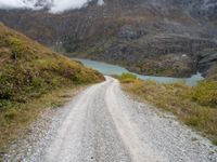 a gravel road in the middle of a scenic area in front of a mountain range