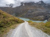 a gravel road in the middle of a scenic area in front of a mountain range