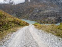 a gravel road in the middle of a scenic area in front of a mountain range