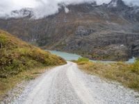 a gravel road in the middle of a scenic area in front of a mountain range