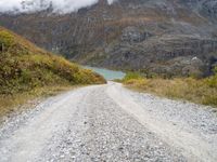 a gravel road in the middle of a scenic area in front of a mountain range