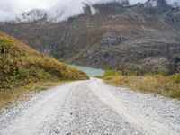 a gravel road in the middle of a scenic area in front of a mountain range