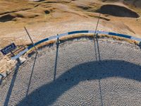 an aerial view of a park that is surrounded by hills and grass and rocks with an empty bench to the side