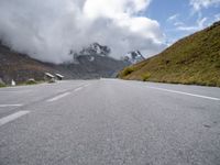 a cloudy sky hangs over an empty road leading towards the mountains on a sunny day