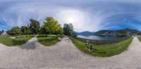 an 360 - degree image showing the same area with one bench and two trees, with a lake and mountains in the background