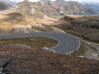 the winding road goes through the mountains into the distance, with bicycle in the foreground