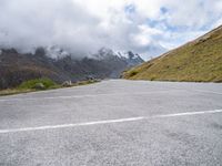 there is an empty asphalt road with mountains in the background, with fog on the ground