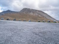 a group of cars that are parked in front of a mountain peak, with a few tent and buildings on the side of the hill