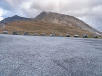 a group of cars that are parked in front of a mountain peak, with a few tent and buildings on the side of the hill