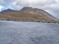 a group of cars that are parked in front of a mountain peak, with a few tent and buildings on the side of the hill