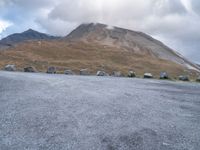 a group of cars that are parked in front of a mountain peak, with a few tent and buildings on the side of the hill