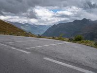 the road is empty and the clouds are coming in on the mountains behind it,