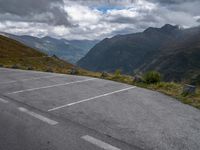 the road is empty and the clouds are coming in on the mountains behind it,