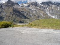 a lone person with an orange jacket sitting next to a motorcycle on the side of a road