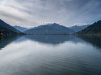 the boat sits in the middle of the calm water and mountains surrounding it are covered with snow capped peaks