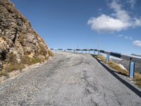 a curve road between two mountains with a blue sky and a bridge in the background