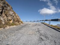 a curve road between two mountains with a blue sky and a bridge in the background