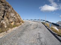 a curve road between two mountains with a blue sky and a bridge in the background