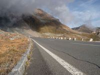 a highway on the side of a mountain under a cloudy sky with some clouds over it