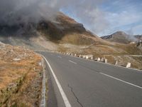 a highway on the side of a mountain under a cloudy sky with some clouds over it