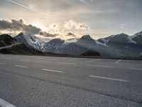 a car is parked along the mountain side near a parking area under some snow covered mountains