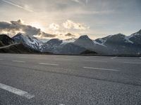 a car is parked along the mountain side near a parking area under some snow covered mountains