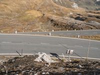 an aerial view of a hill with mountains in the distance and sign posts at the center of the road