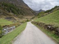 a small rural road surrounded by mountains and trees is pictured in this photo with a sky background