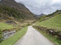 a small rural road surrounded by mountains and trees is pictured in this photo with a sky background