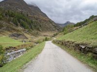 a small rural road surrounded by mountains and trees is pictured in this photo with a sky background