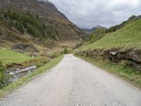 a small rural road surrounded by mountains and trees is pictured in this photo with a sky background