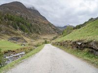 a small rural road surrounded by mountains and trees is pictured in this photo with a sky background