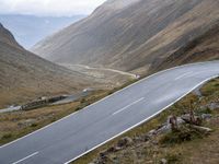 the road goes through the mountains into the mountains as a motorcyclist rides by on it