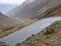 the road goes through the mountains into the mountains as a motorcyclist rides by on it