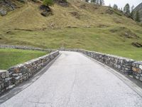 a road passing through the mountains next to a hill with a gate on it,