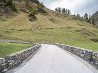 a road passing through the mountains next to a hill with a gate on it,