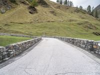 a road passing through the mountains next to a hill with a gate on it,