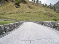 a road passing through the mountains next to a hill with a gate on it,