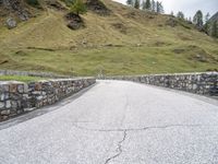 a road passing through the mountains next to a hill with a gate on it,