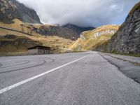 the mountain road has white lines painted on it and is surrounded by mountains and hills