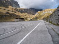 the mountain road has white lines painted on it and is surrounded by mountains and hills