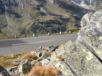 there is a large mountain range on the side of the road with rocks and grass on both sides