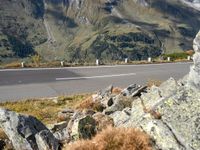 there is a large mountain range on the side of the road with rocks and grass on both sides