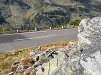 there is a large mountain range on the side of the road with rocks and grass on both sides