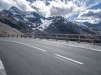 a road leading to the mountains on a partly sunny day with clouds and mountains in the background