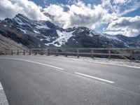 a road leading to the mountains on a partly sunny day with clouds and mountains in the background