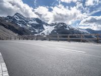 a road leading to the mountains on a partly sunny day with clouds and mountains in the background