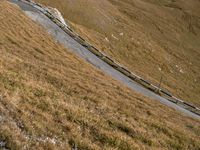 a steep winding road winds up into the mountains of scotland, which is covered with brown grass